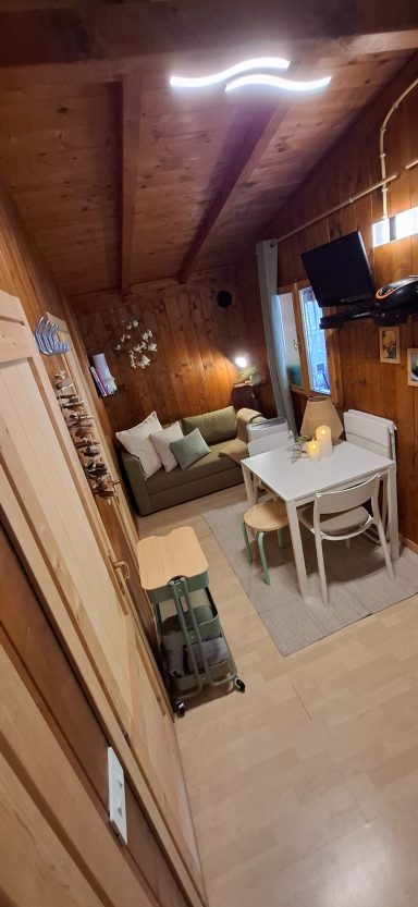 Compleet ingerichte accommodatie Luganomeer Een knusse zithoek met een bank, tafel en lampen in een houten interieur.